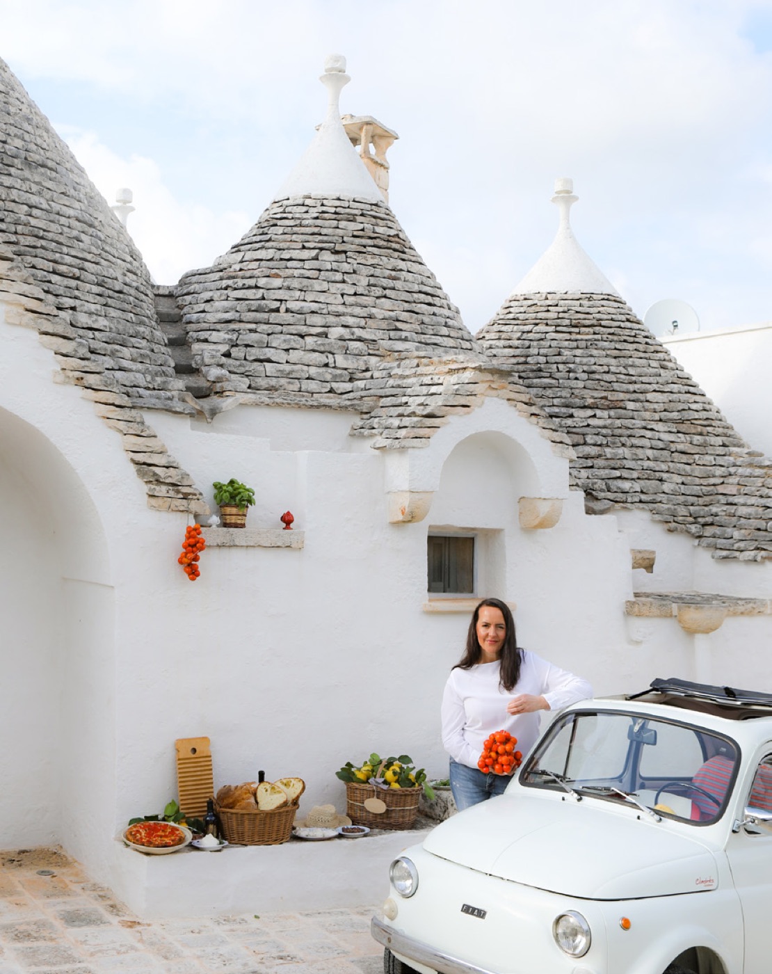 Trulli in Apulien – Stefania Lettini vor einem weiß getünchten Trullo mit Fiat 500