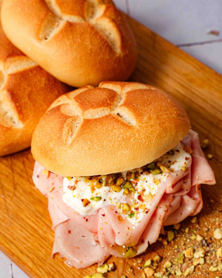 Il Panino di Willie auf dem Holzbrett, dahinter frische Panini