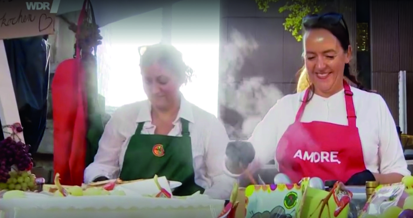 Standbild aus der WDR Lokalzeit: Stefania Lettini in der Amore-Schürze am Stand der Piazza Italia auf der Königsallee